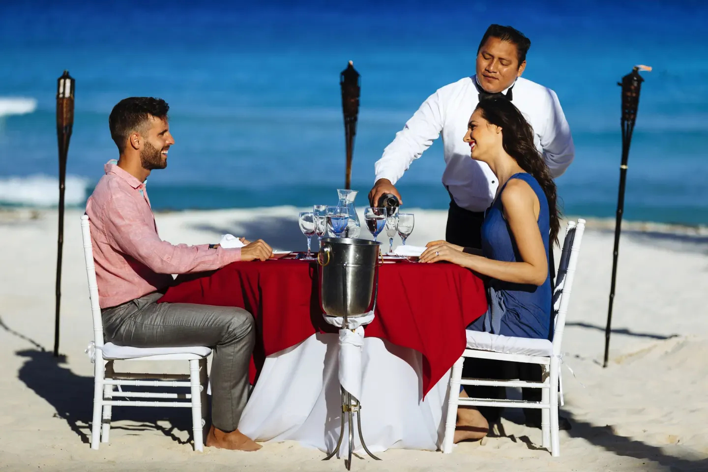 Beachfront dinner table with ocean backdrop and waiter service at Occidental Tucancún.