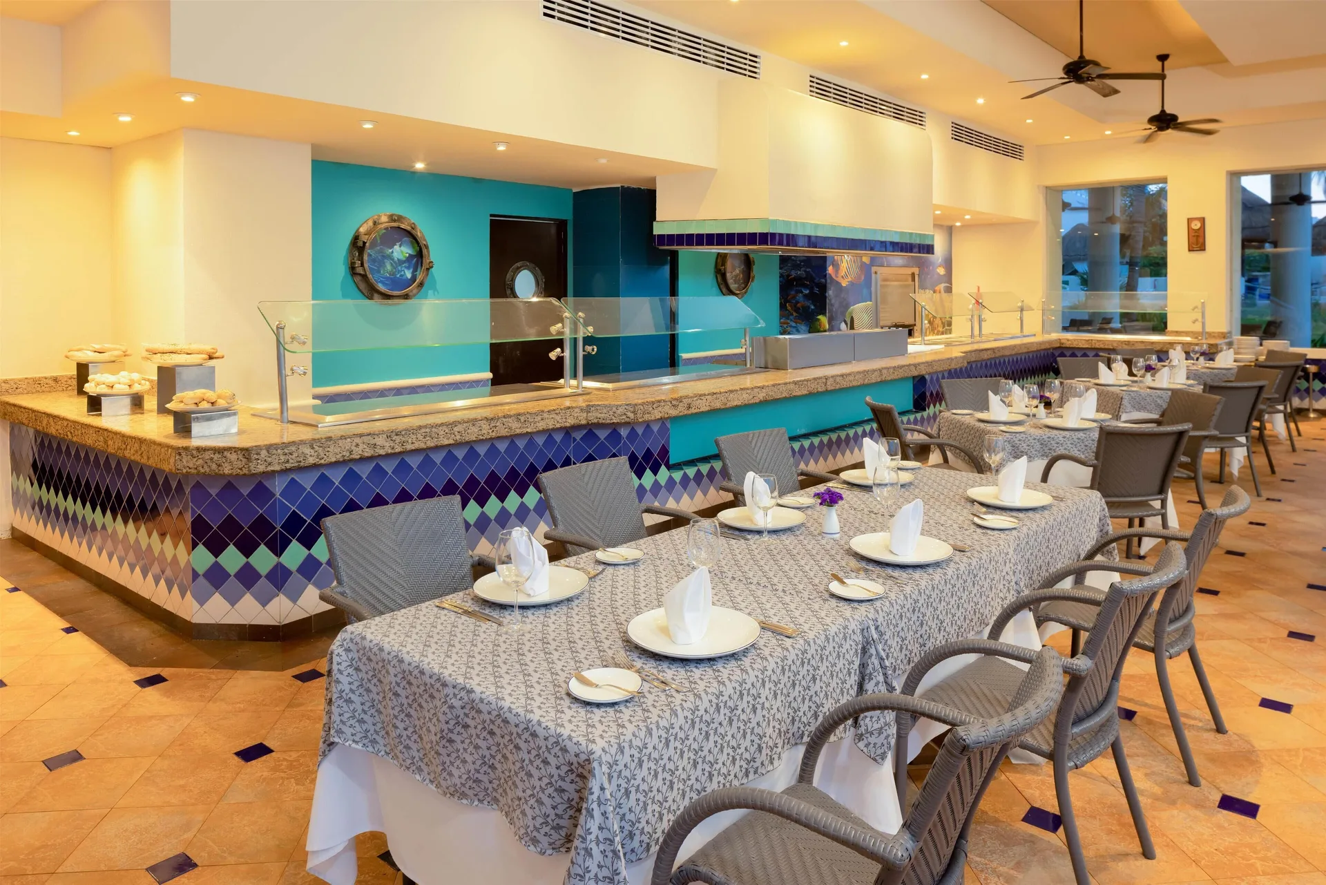 Seafood restaurant dining room with set tables and blue tile accents at Occidental Tucancún.