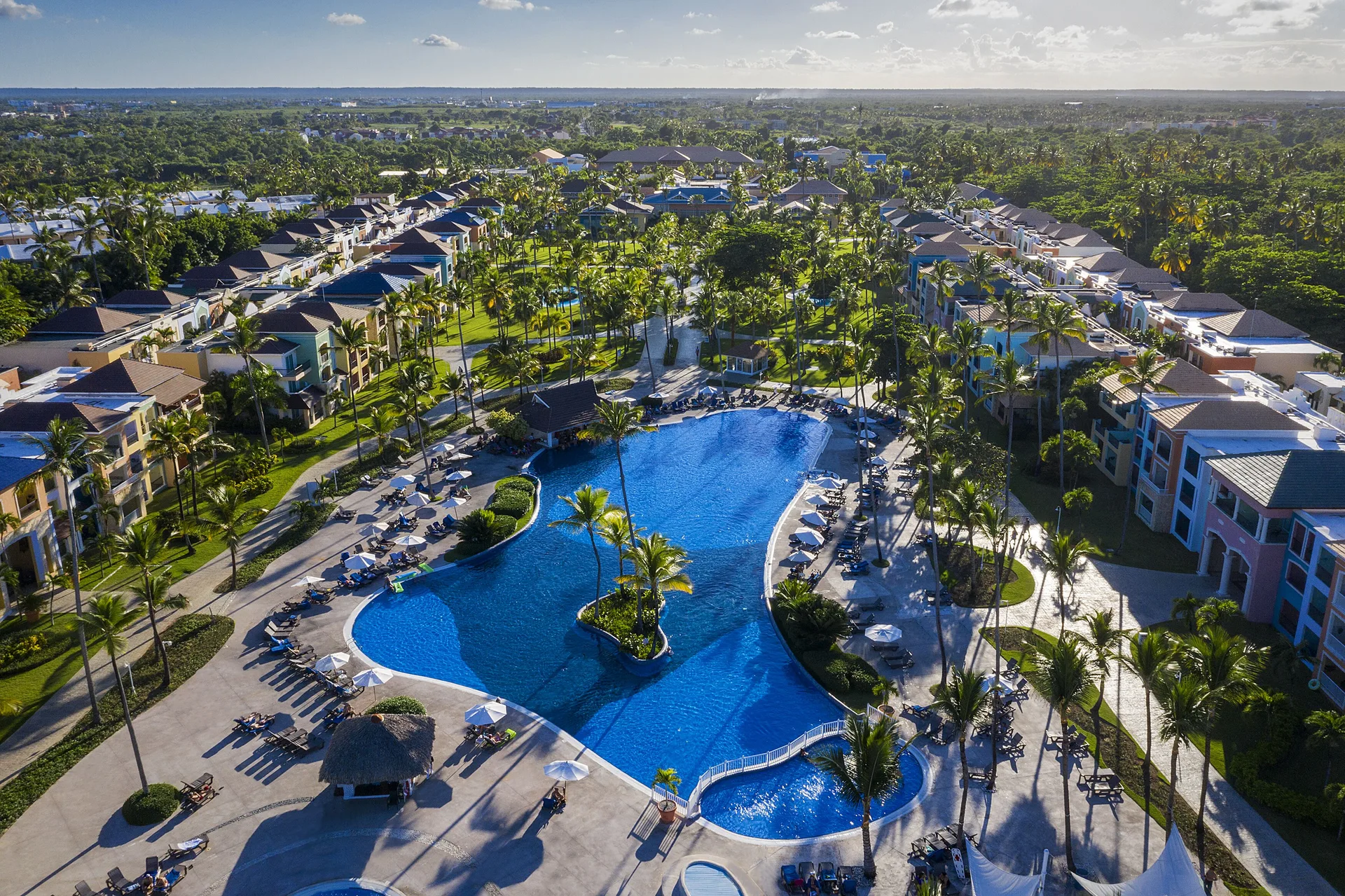 Aerial view of the main pool and palm-lined buildings at Ocean Blue & Sand Beach Resort.
