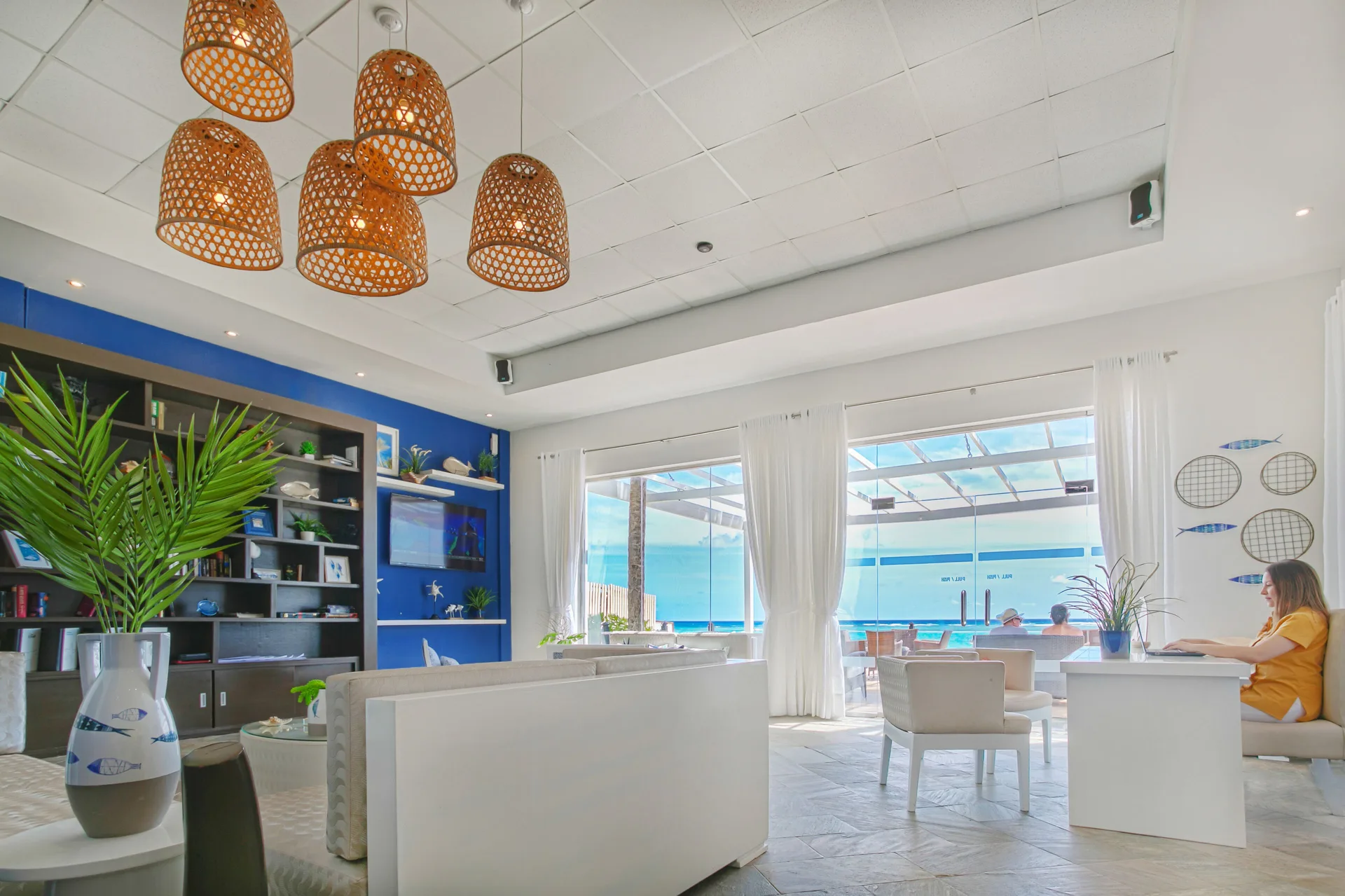 Bright beachside room with white sofas and ocean-facing doors at Ocean Blue & Sand Beach Resort.