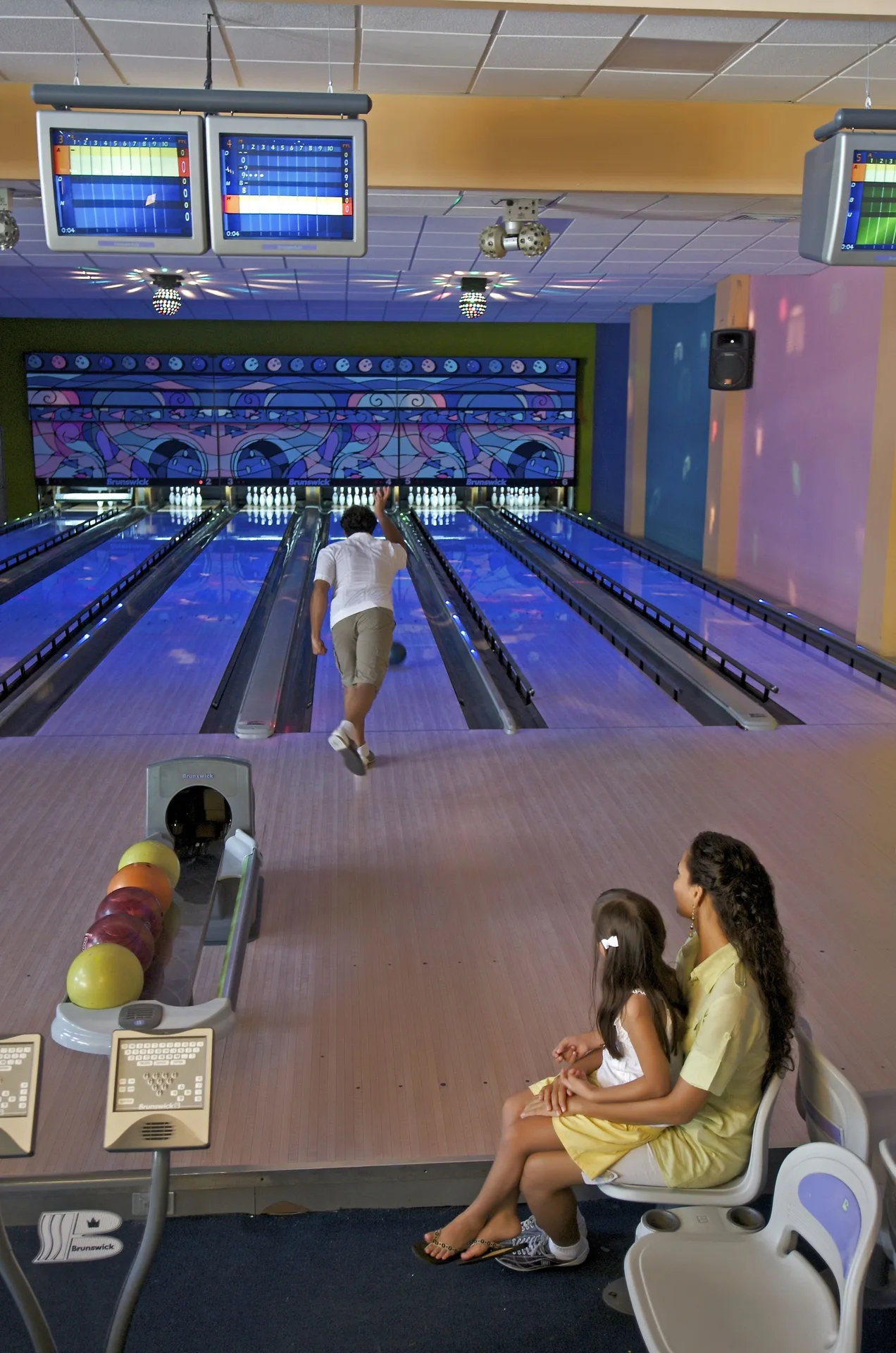 A guest bowls while two people watch in the alley at Ocean Blue & Sand Beach Resort.