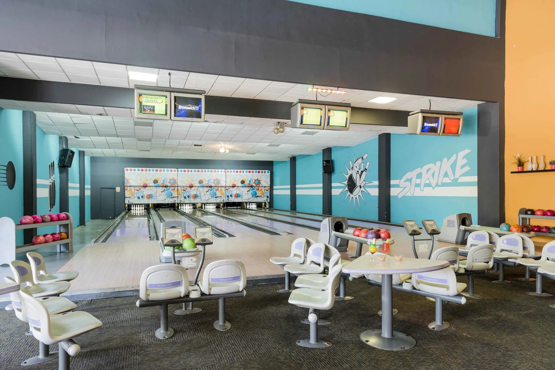Bowling alley with lanes, score monitors, and seating at Ocean Blue & Sand Beach Resort.