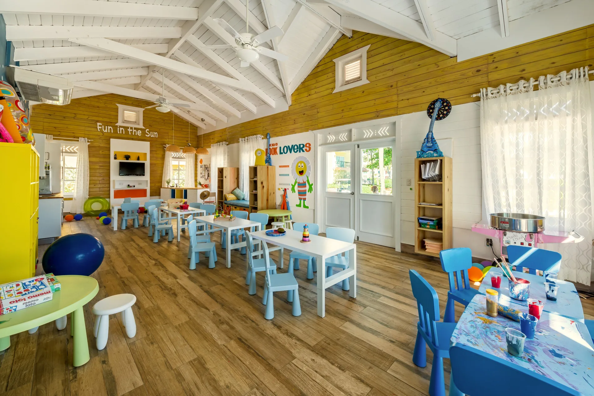 Children's activity room with small tables, blue chairs and toys at Ocean Blue & Sand Beach Resort.