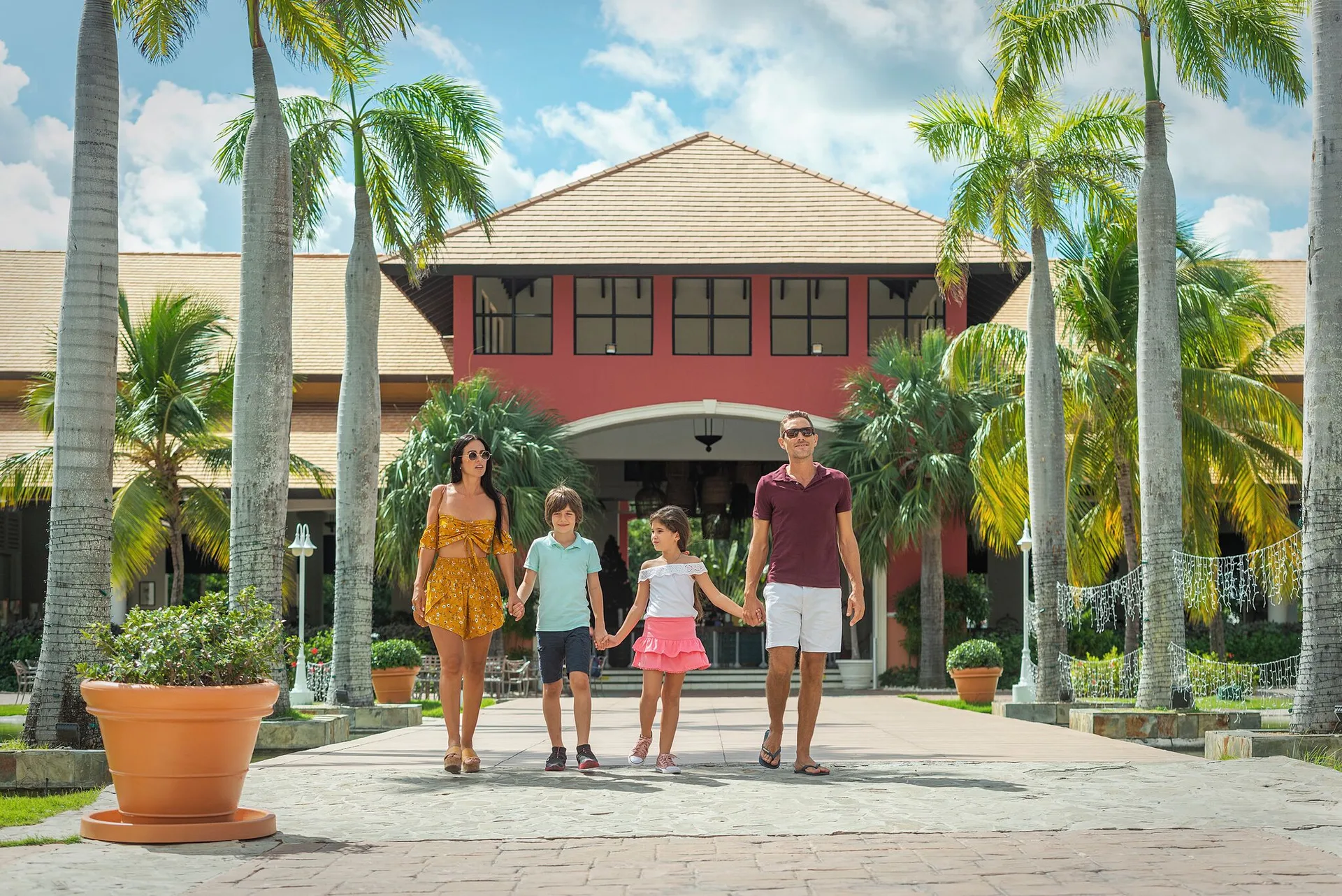 Family walking between palm trees at the resort entrance at Ocean Blue & Sand Beach Resort.