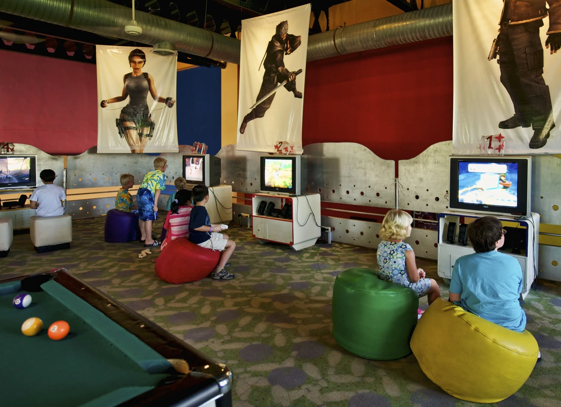 Children play video games beside a pool table in the game room at Ocean Blue & Sand Beach Resort.