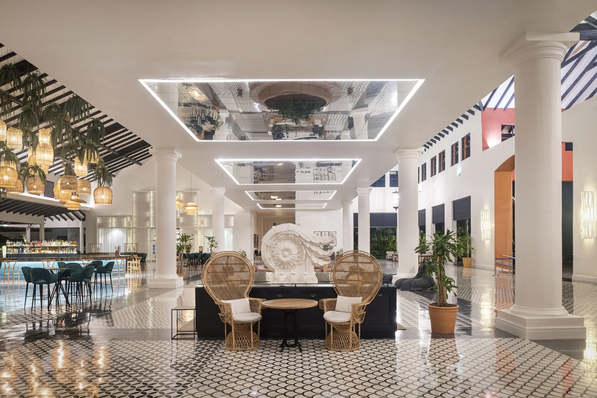 Bright lobby lounge and bar area at Ocean Blue & Sand Beach Resort with columns and wicker chairs.
