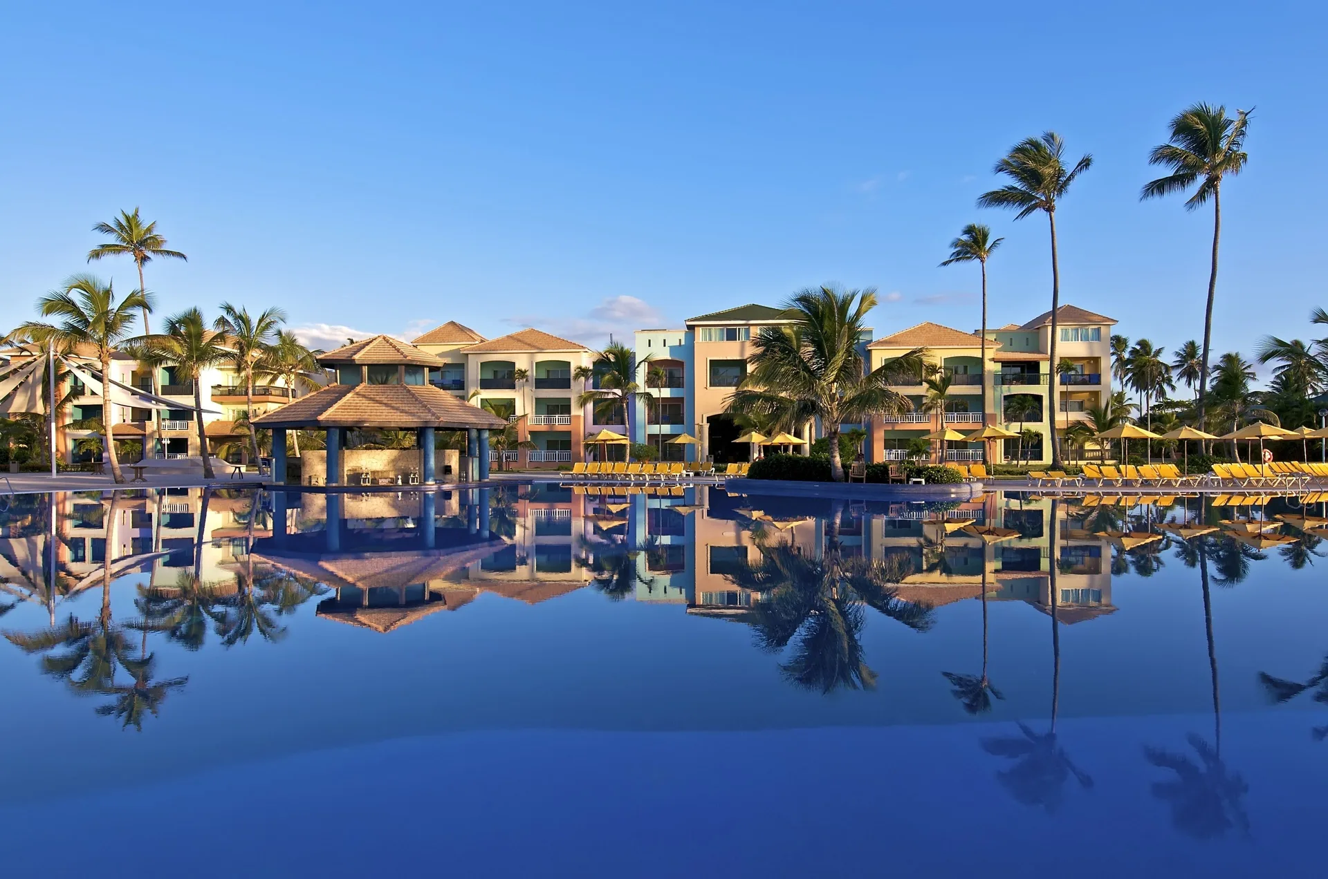 Pool pavilion, palms and resort buildings reflected at Ocean Blue & Sand Beach Resort.