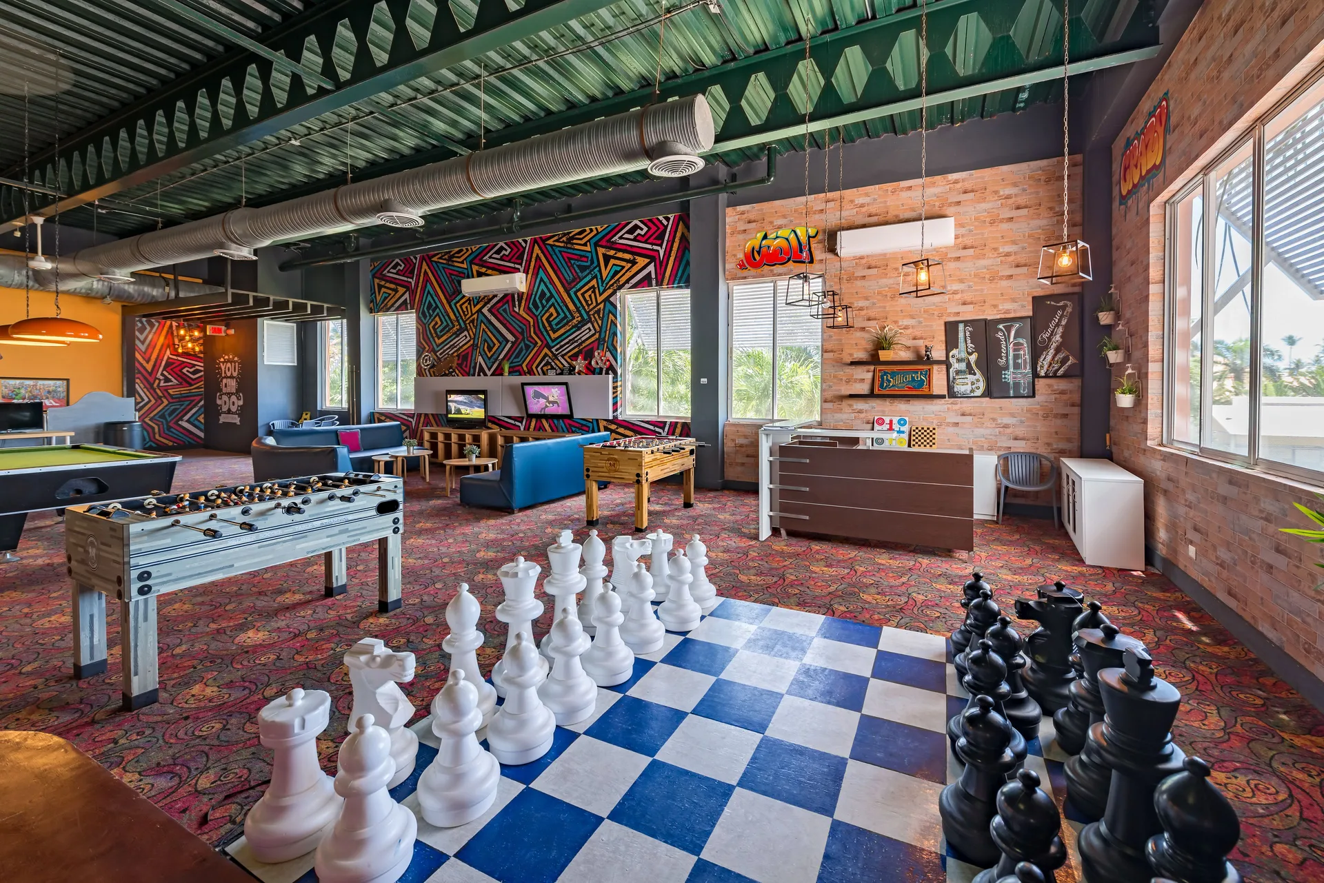 Teen game room with giant chess, foosball, and lounge seating at Ocean Blue & Sand Beach Resort.