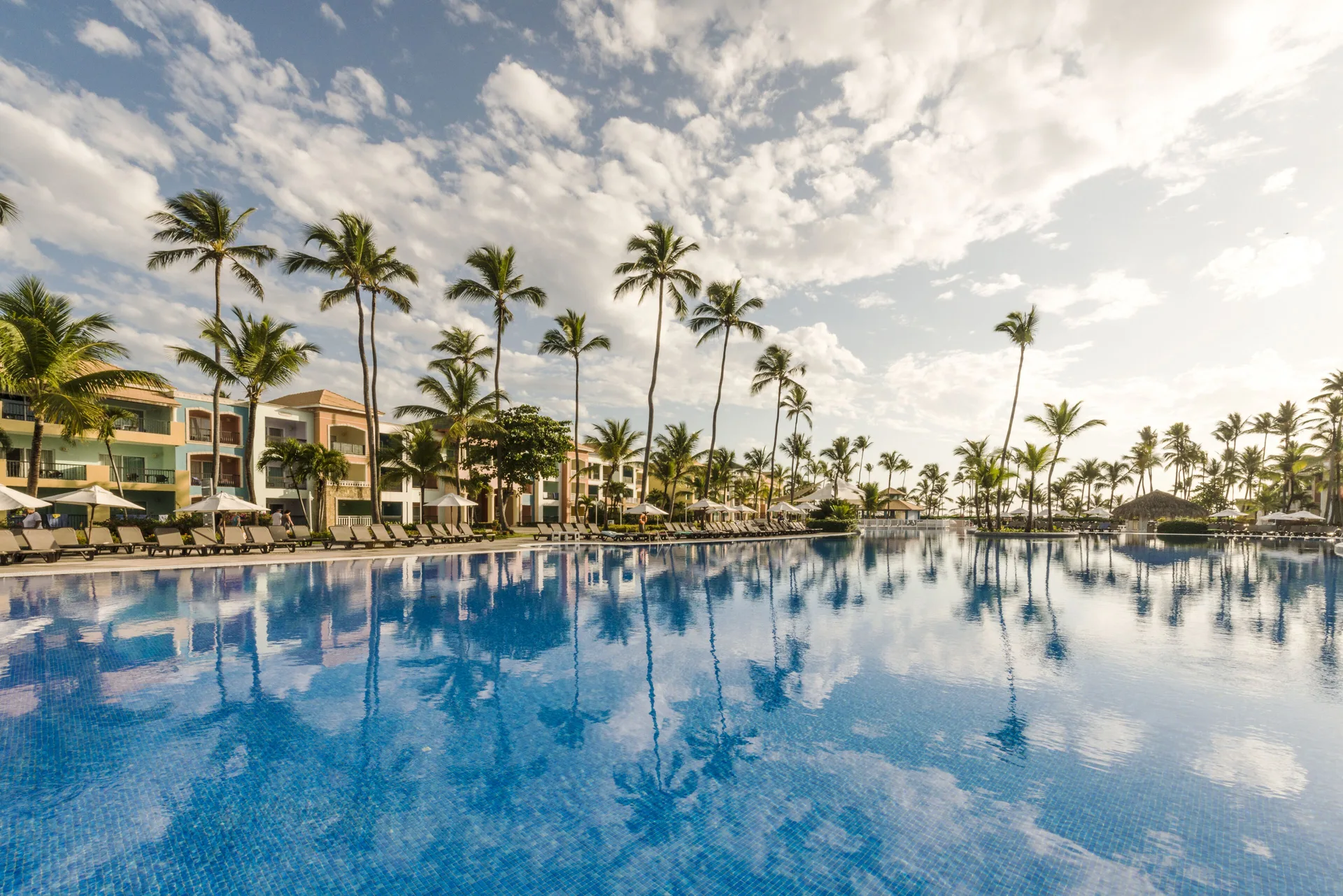 Wide pool view with tall palms and lounge chairs at Ocean Blue & Sand Beach Resort.