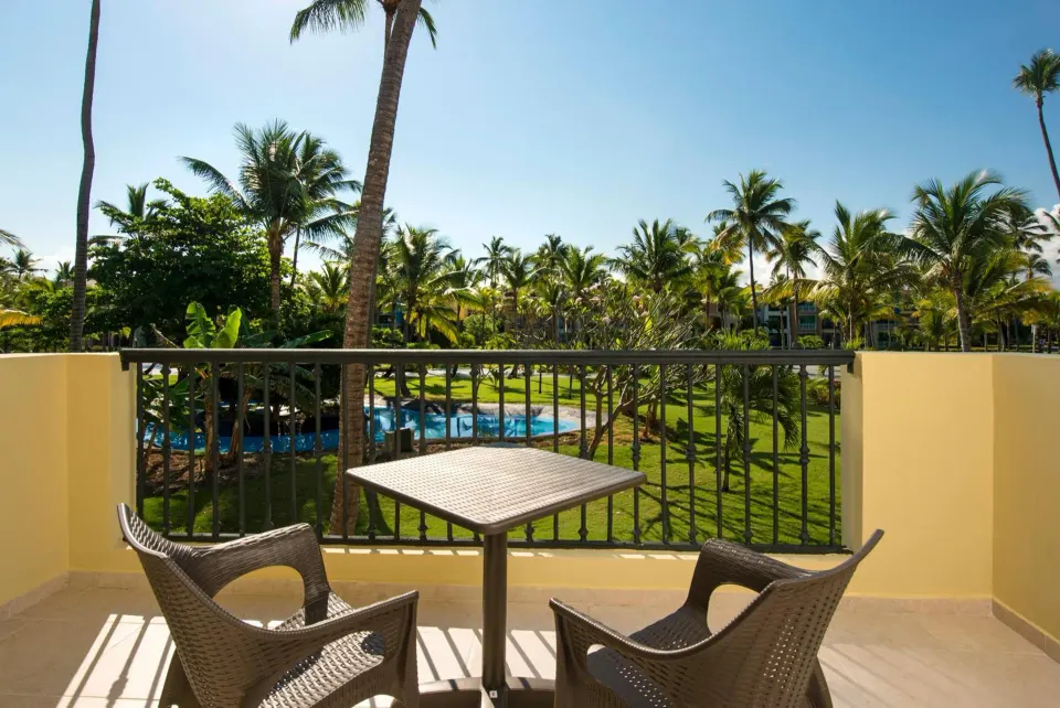 Junior Suite balcony with table, chairs and palm views at Ocean Blue & Sand Beach Resort.