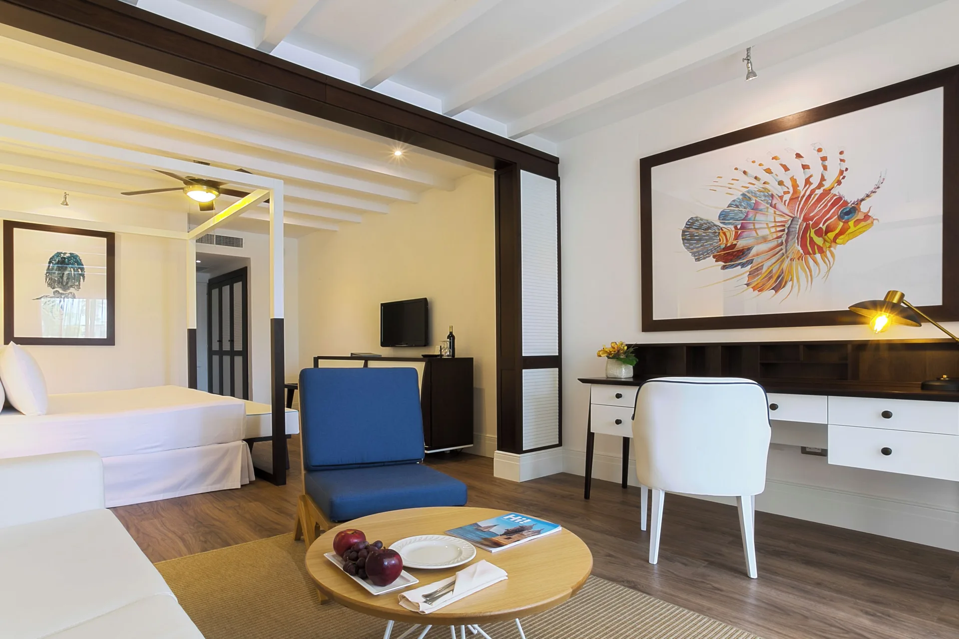 Junior Suite Elegance Nature View with bed, lounge chair, desk, and fish art at Ocean Blue & Sand Beach Resort.
