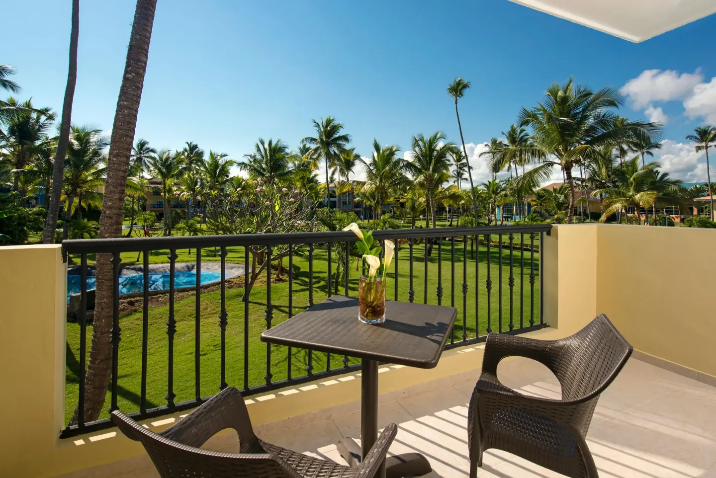 Junior Suite Nature View balcony with table and palm garden at Ocean Blue & Sand Beach Resort.