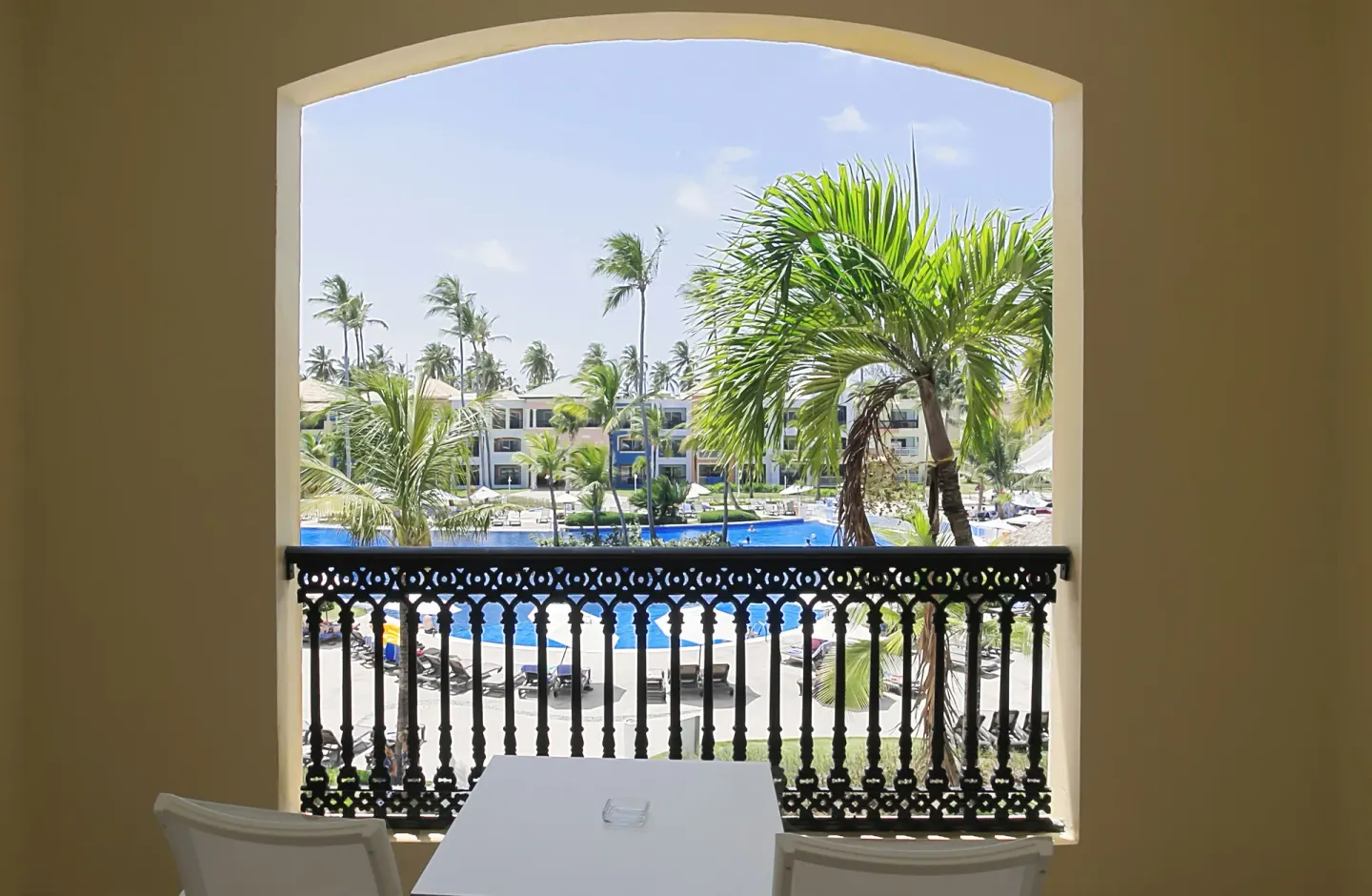 Junior Suite Pool View balcony at Ocean Blue & Sand Beach Resort overlooking palms and the pool.