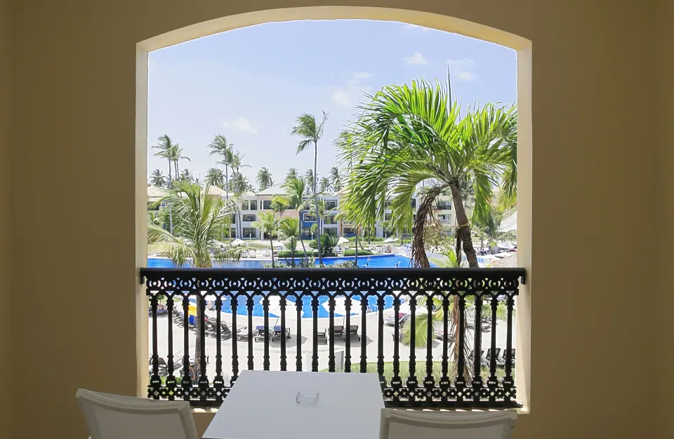 Junior Suite Pool View balcony at Ocean Blue & Sand Beach Resort overlooking palms and the pool.