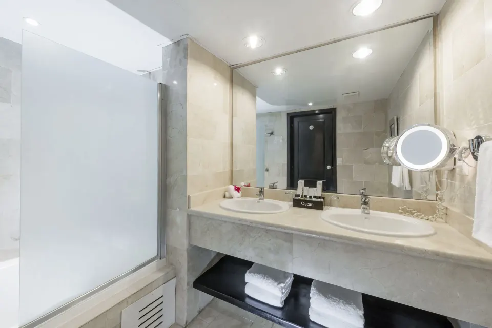 Bathroom with double sinks and glass shower at Ocean Blue & Sand Beach Resort.