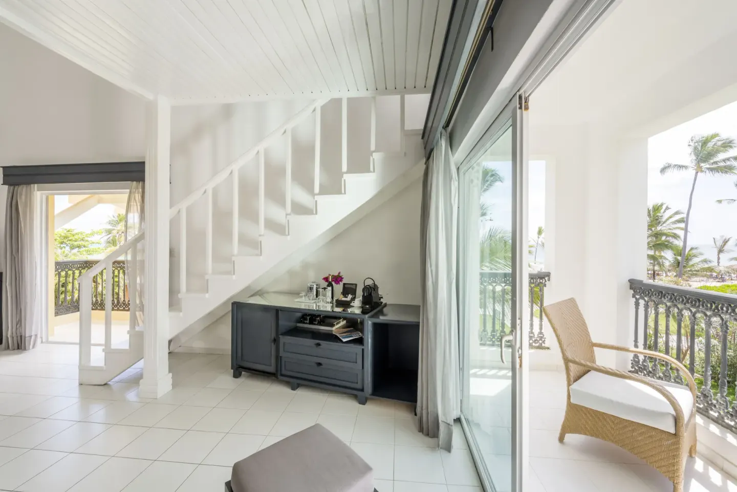 Staircase, balcony seating, and palm views in a Privilege Honeymoon Suite at Ocean Blue & Sand Beach Resort.