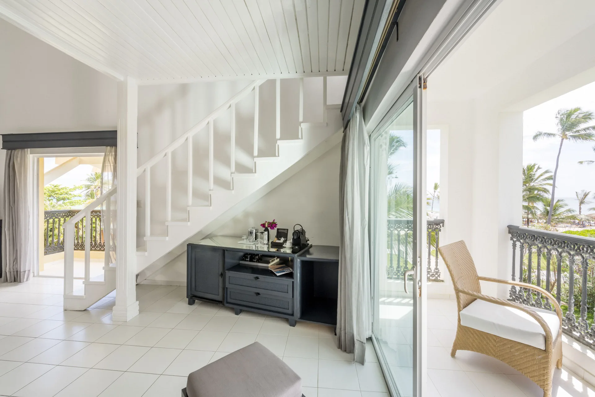 Staircase, balcony seating, and palm views in a Privilege Honeymoon Suite at Ocean Blue & Sand Beach Resort.