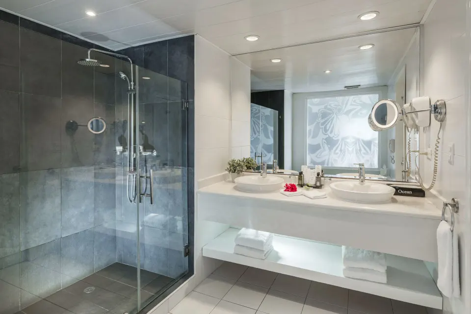 Bathroom with glass shower and double sinks in a Privilege Honeymoon Suite at Ocean Blue & Sand Beach Resort.
