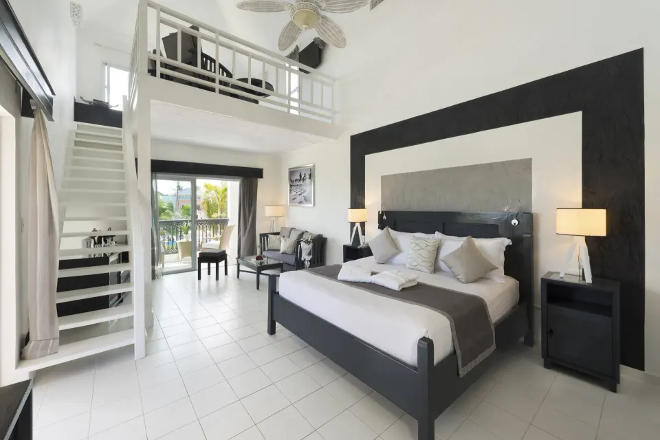 King bed, loft stairs, and balcony doors in a Privilege Honeymoon Suite at Ocean Blue & Sand Beach Resort.
