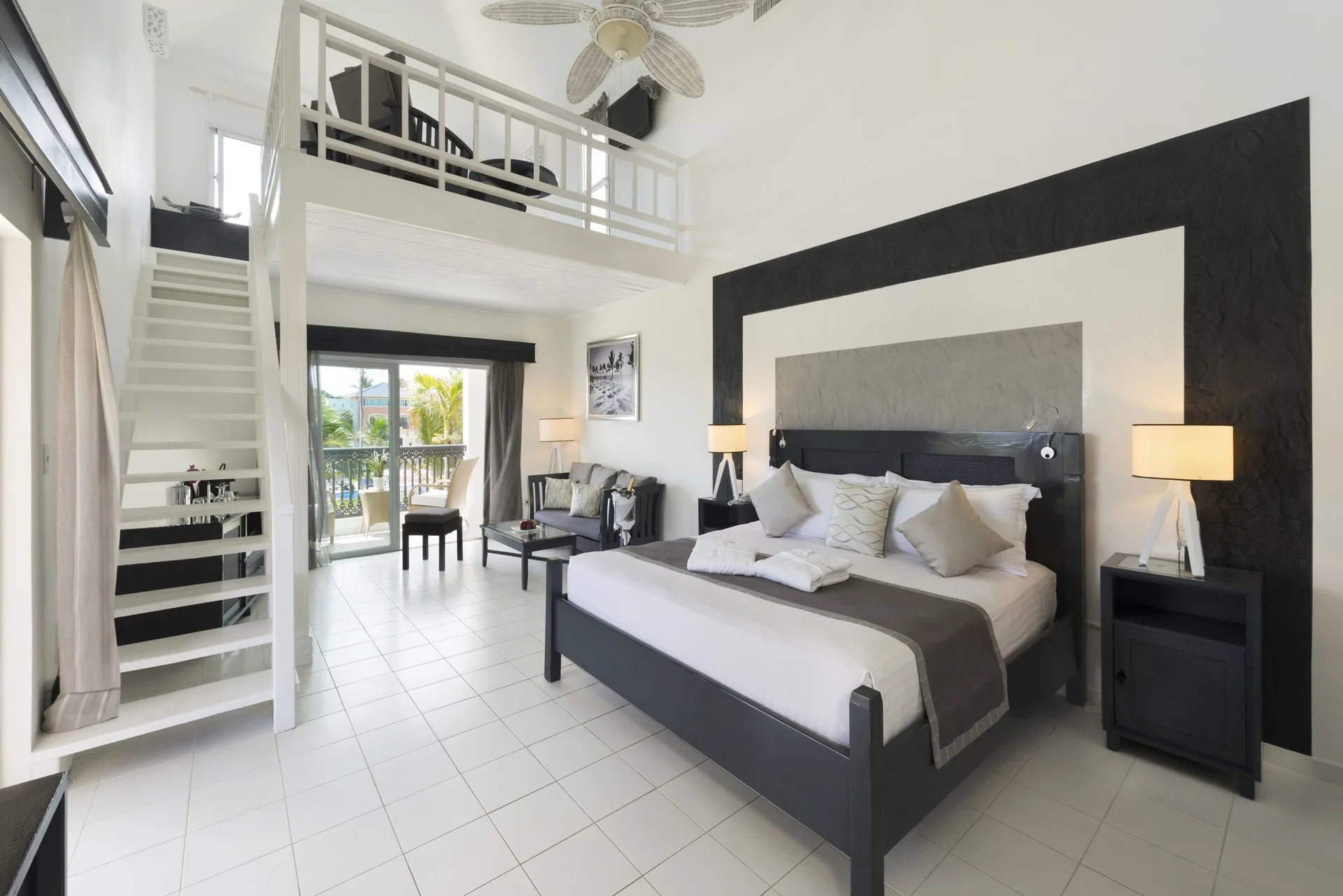 King bed, loft stairs, and balcony doors in a Privilege Honeymoon Suite at Ocean Blue & Sand Beach Resort.