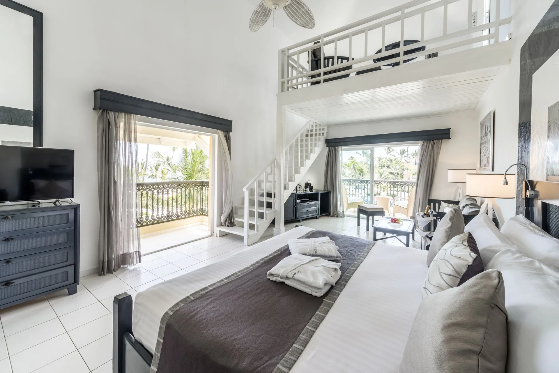 King bed, TV dresser, loft, and balconies in a Privilege Honeymoon Suite at Ocean Blue & Sand Beach Resort.