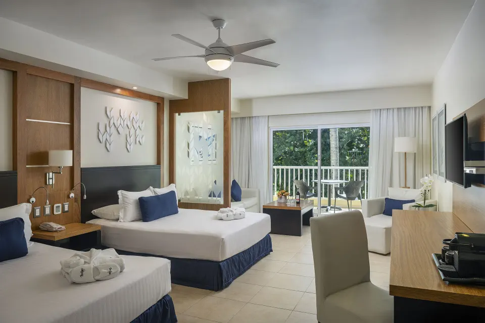 Privilege Junior Suite Nature View beds, desk, and balcony doors at Ocean Blue & Sand Beach Resort.