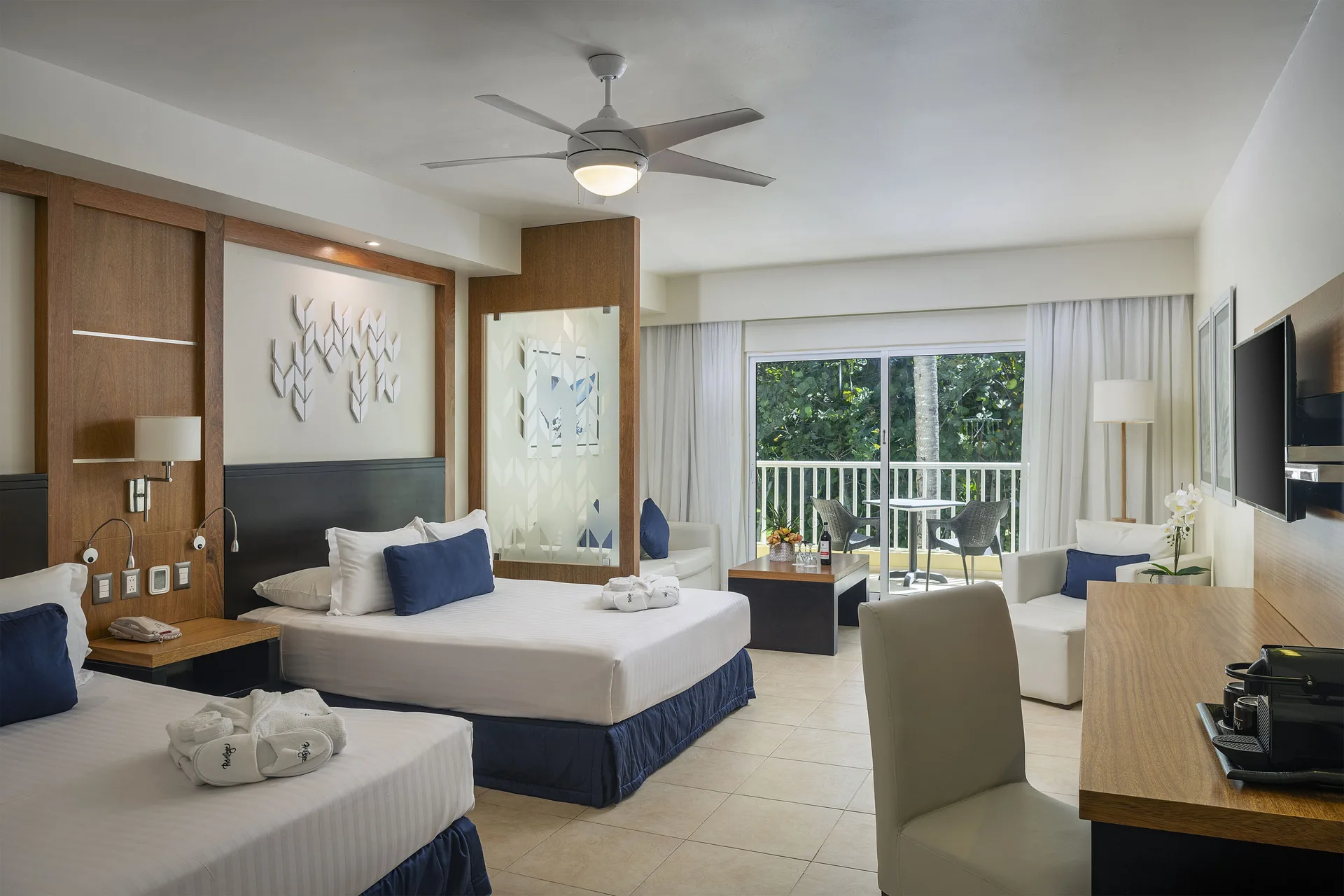Privilege Junior Suite Nature View beds, desk, and balcony doors at Ocean Blue & Sand Beach Resort.