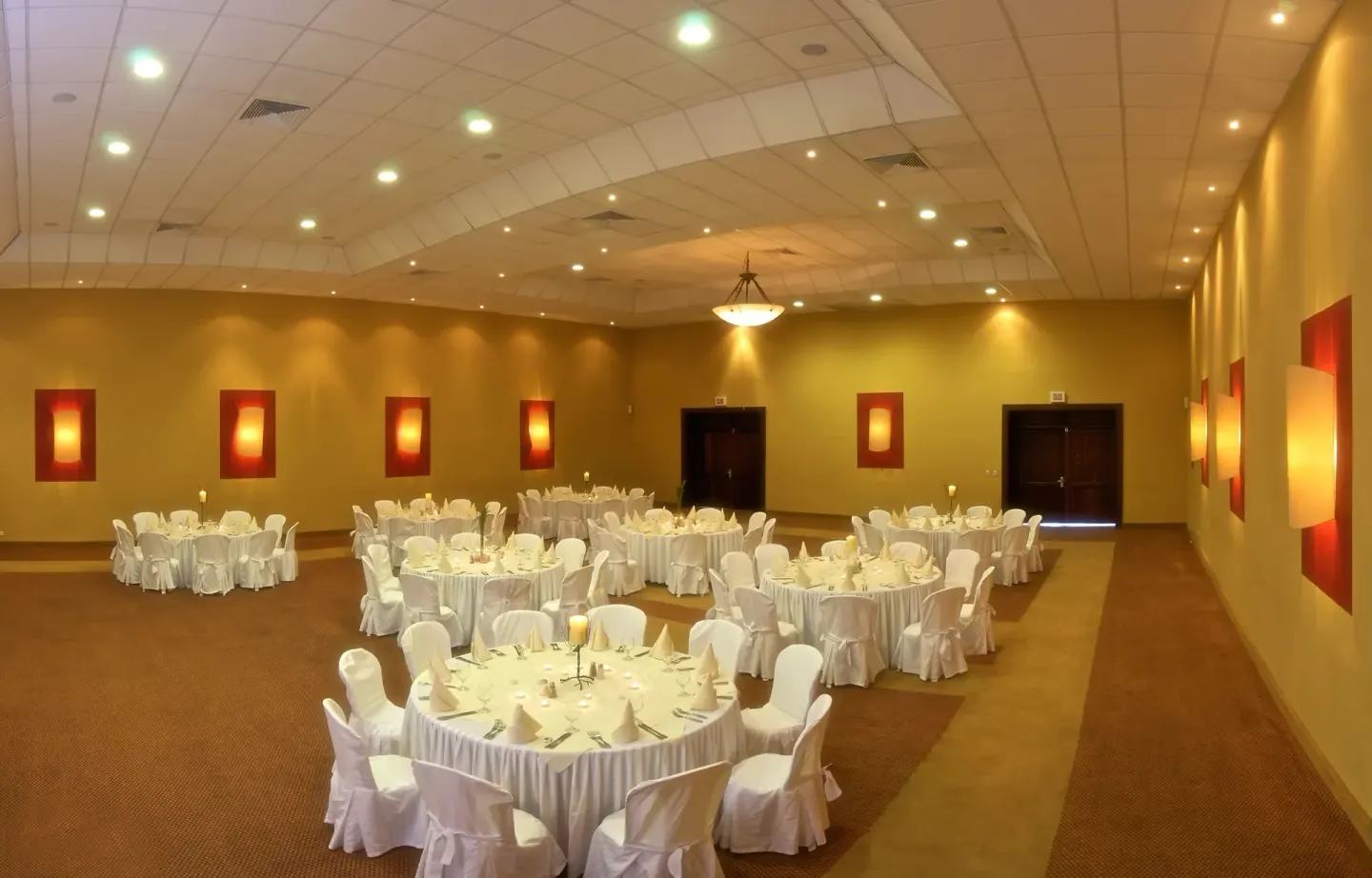 Banquet room with round tables and white chair covers at Ocean Blue & Sand Beach Resort.