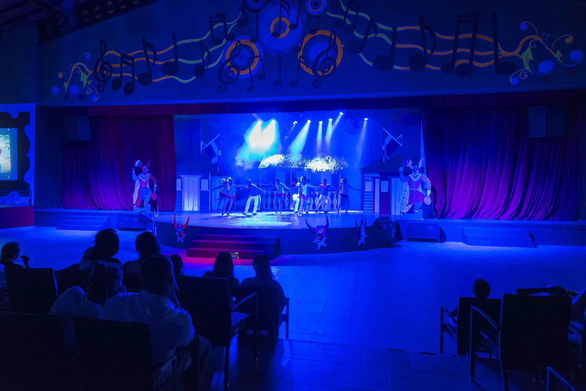 Blue-lit stage show with dancers and seated audience at Ocean Blue & Sand Beach Resort.
