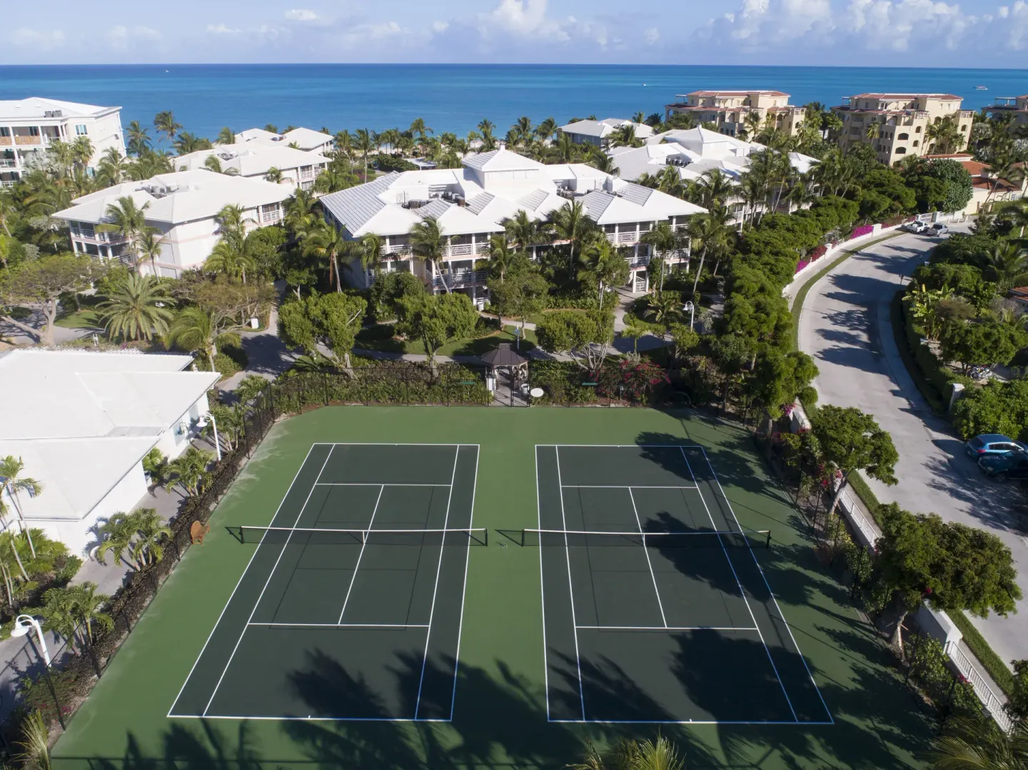 Aerial view of tennis courts, resort buildings, and ocean at Ocean Club West, Grace Bay Beach.