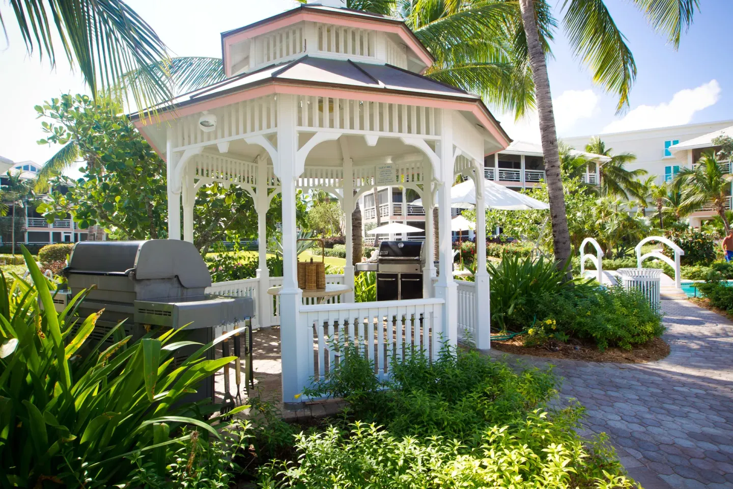 A white garden gazebo with grills stands by the pool area at Ocean Club West, Grace Bay Beach.