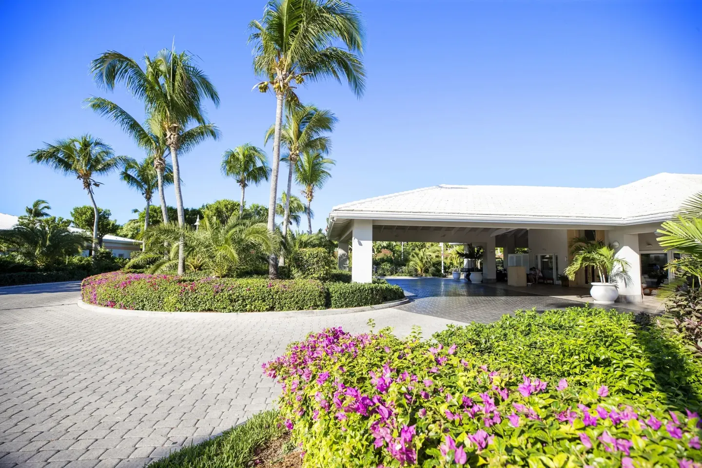 Palm-lined entrance drive and covered arrival area at Ocean Club West, Grace Bay Beach.