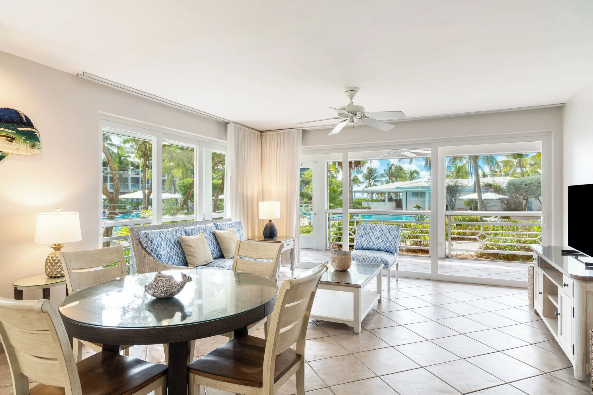 Bright living and dining area with poolside windows at Ocean Club West, Grace Bay Beach.
