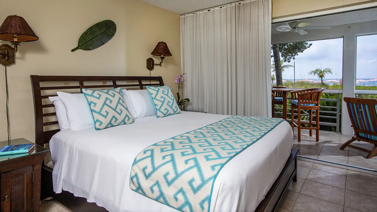 Beachfront two-bedroom deluxe suite king bedroom and balcony at Ocean Club West, Grace Bay Beach.
