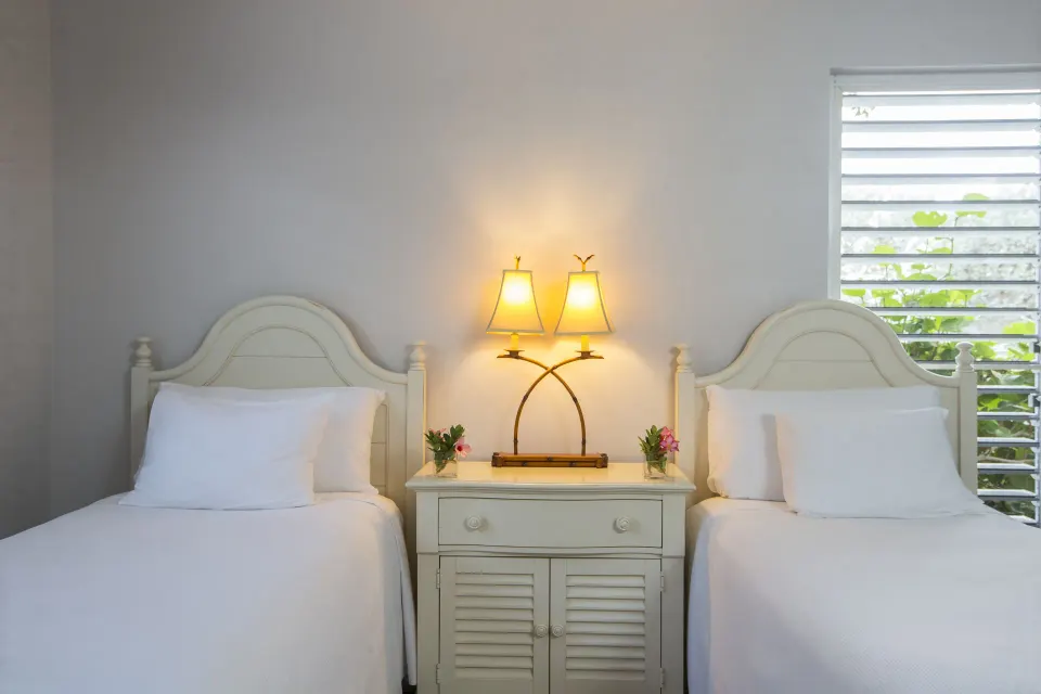 White twin beds and nightstand in a beachfront deluxe suite at Ocean Club West, Grace Bay Beach.