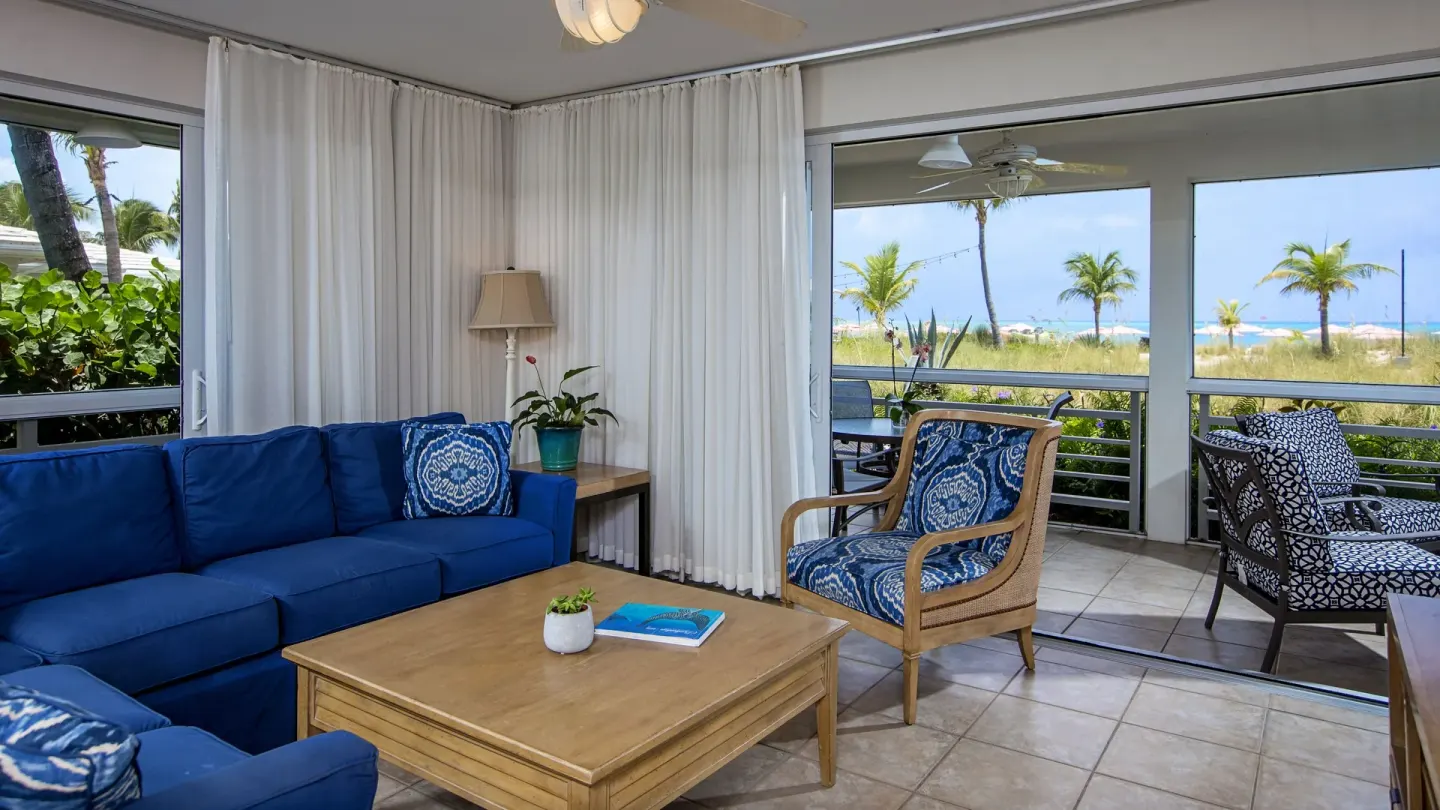 Blue seating and beach-facing patio in a Deluxe Two Bedroom Suite at Ocean Club West, Grace Bay Beach.