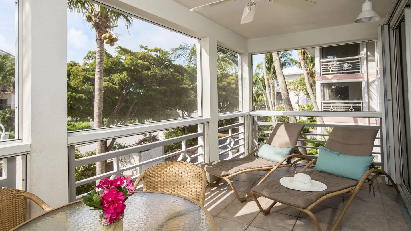Studio suite screened balcony with loungers and palm views at Ocean Club West, Grace Bay Beach.
