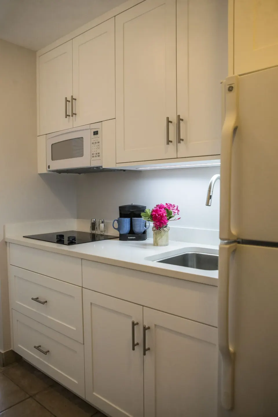 Studio suite kitchenette with sink, cooktop, microwave, and refrigerator at Ocean Club West, Grace Bay Beach.