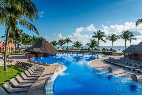 Large beachfront pool with loungers and palapa shade at Ocean Coral and Turquesa.