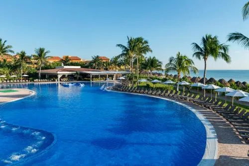 Curved resort pool lined with loungers at Ocean Coral and Turquesa.