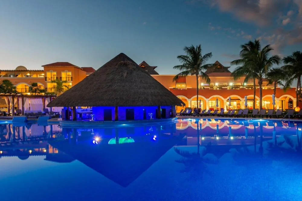 Illuminated main pool with thatched swim-up bar at Ocean Coral and Turquesa.