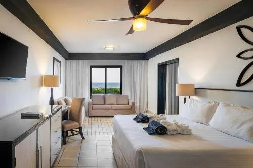 King bed guest room with sofa, desk, and balcony view at Ocean Coral and Turquesa.