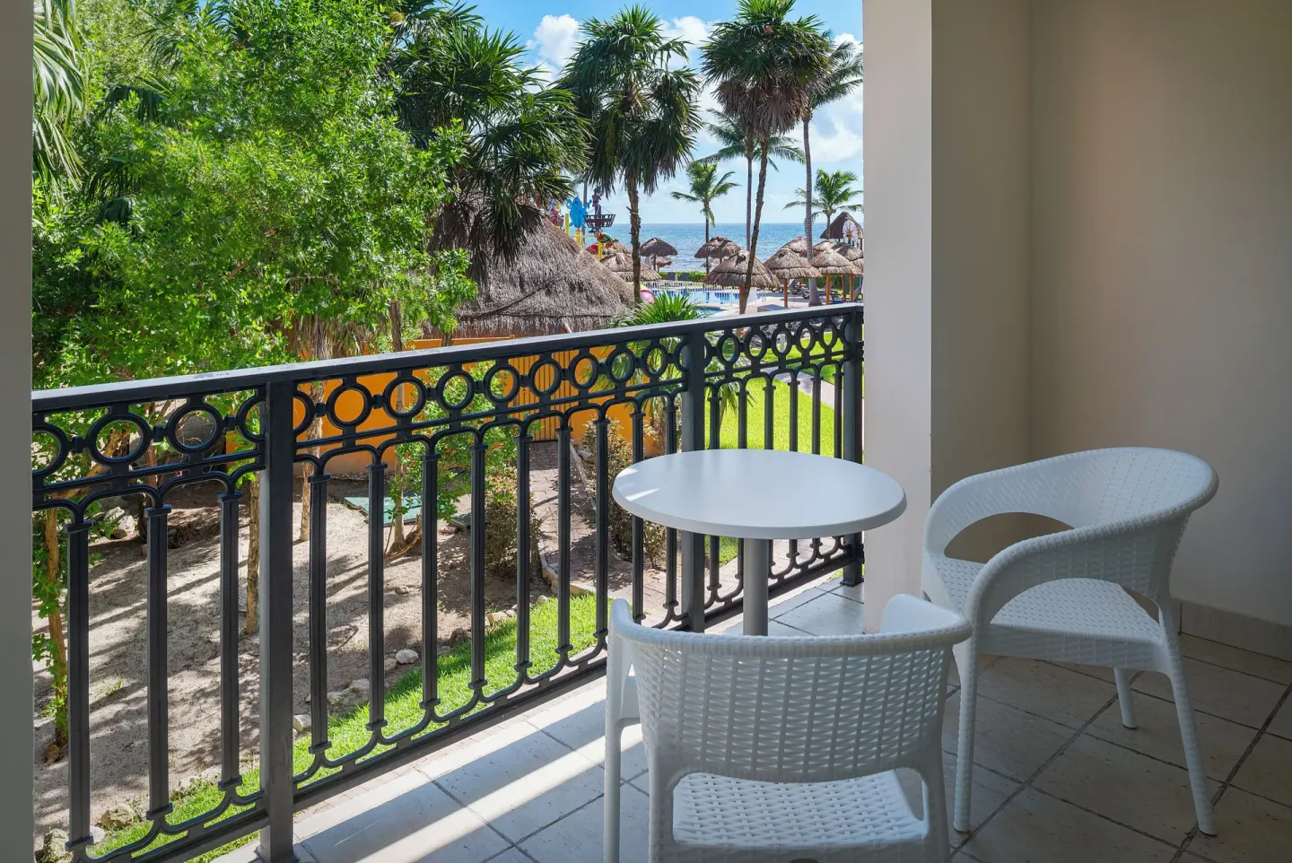 Junior Suite Waterpark Side Ocean Coral and Turquesa balcony at Ocean Coral and Turquesa with table, chairs, and palms.