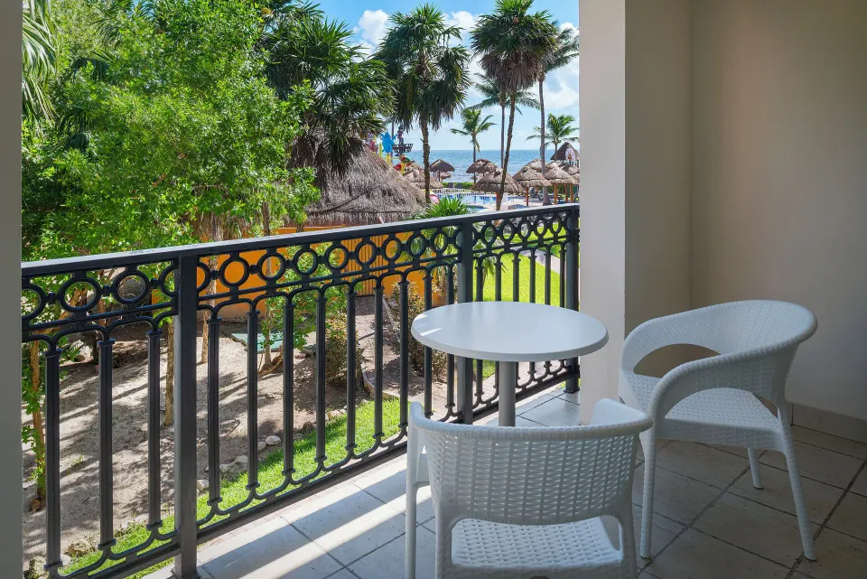 Junior Suite Waterpark Side Ocean Coral and Turquesa balcony at Ocean Coral and Turquesa with table, chairs, and palms.