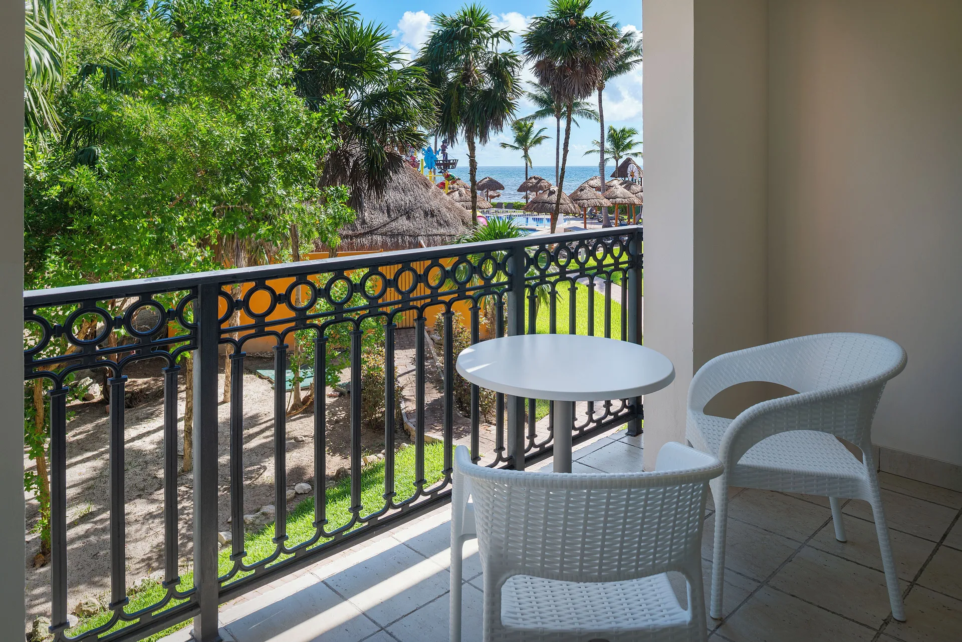 Junior Suite Waterpark Side Ocean Coral and Turquesa balcony at Ocean Coral and Turquesa with table, chairs, and palms.
