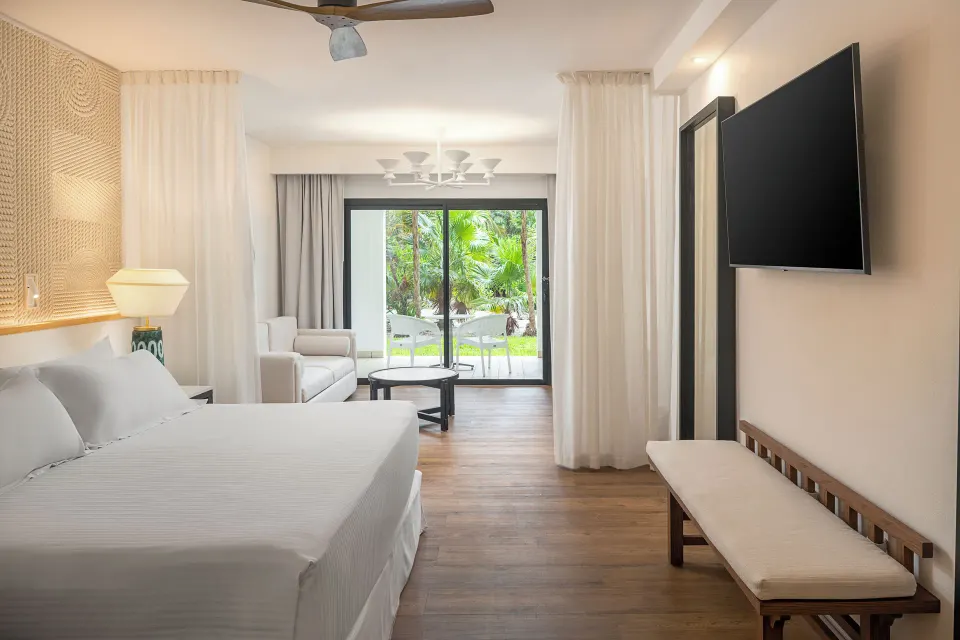 Junior Suite Waterpark Side king bed facing terrace and TV at Ocean Coral and Turquesa.