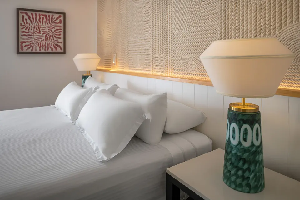 Junior Suite Waterpark Side king bed pillows and bedside lamp at Ocean Coral and Turquesa.