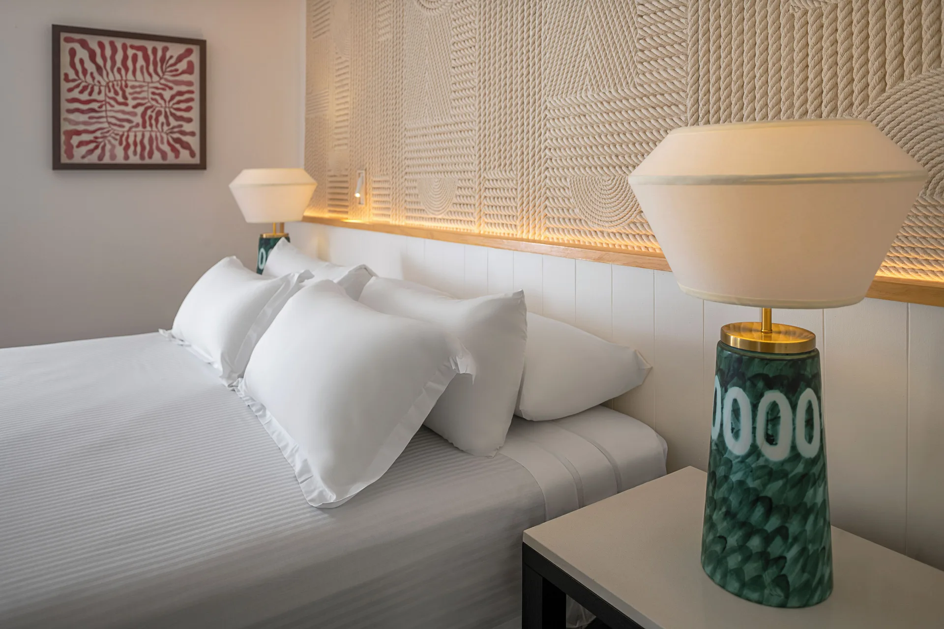 Junior Suite Waterpark Side king bed pillows and bedside lamp at Ocean Coral and Turquesa.