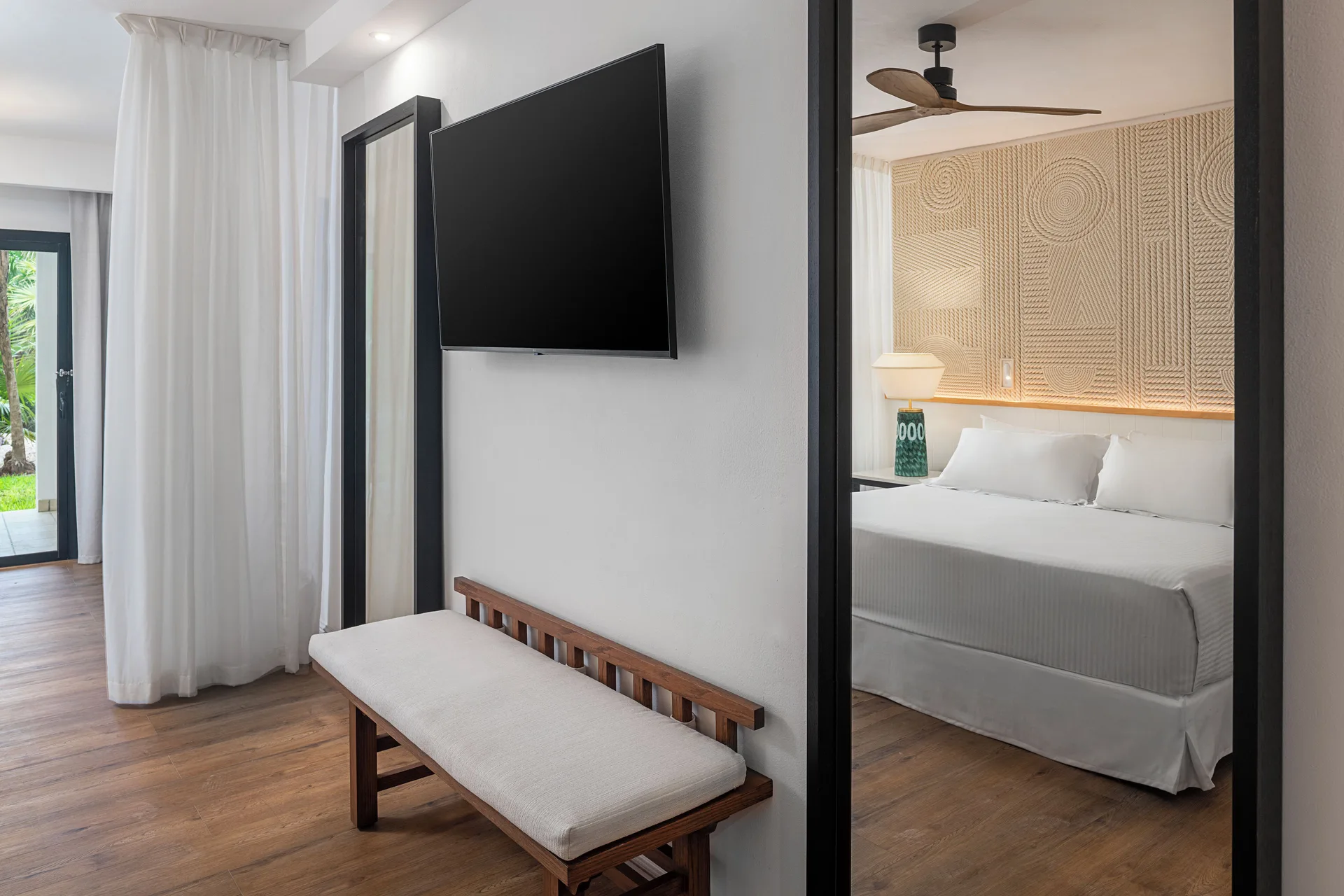 Junior Suite Waterpark Side TV wall, bench, and king bed at Ocean Coral and Turquesa.