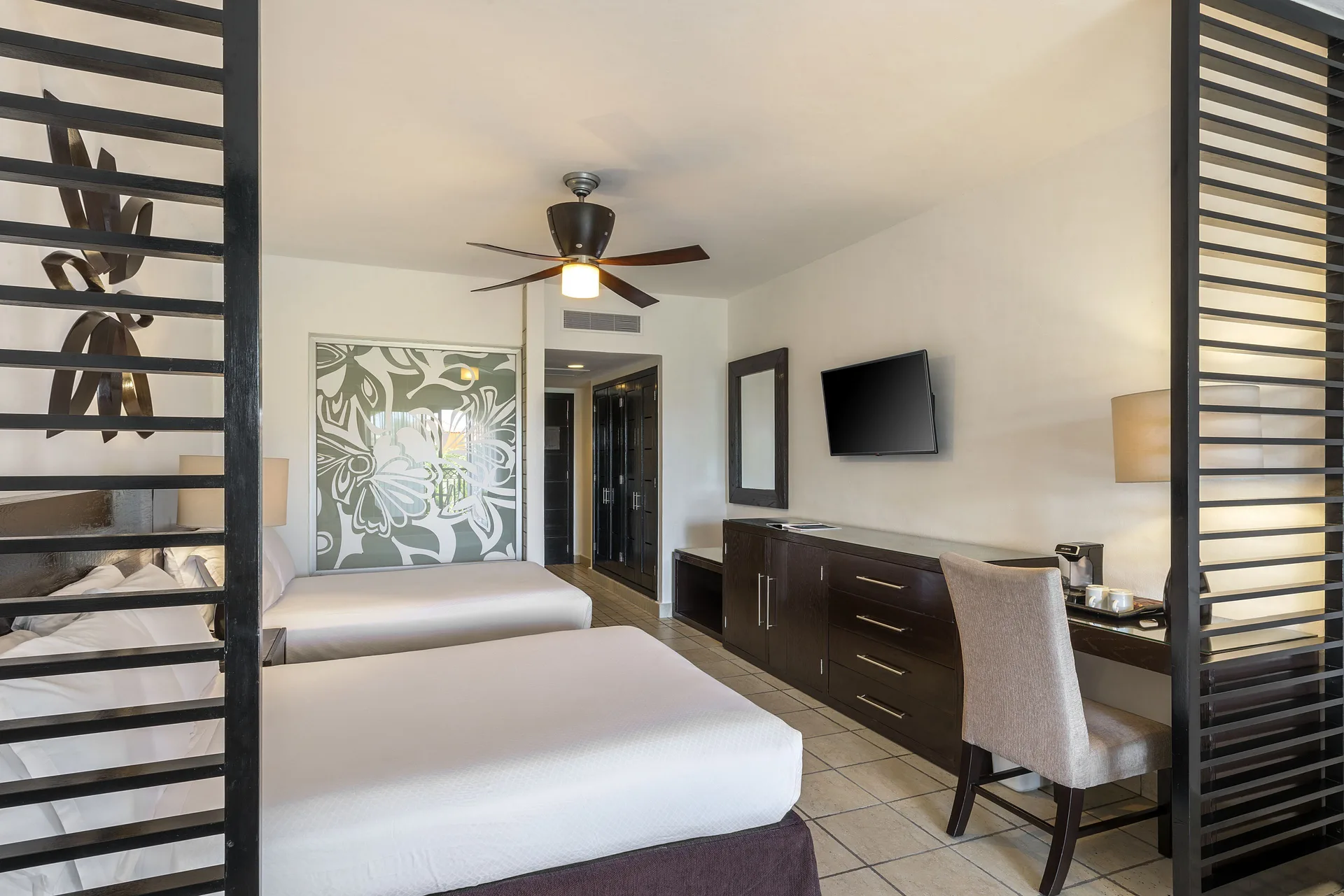 Junior Suite Waterpark Side two beds, desk, dresser, and TV at Ocean Coral and Turquesa.
